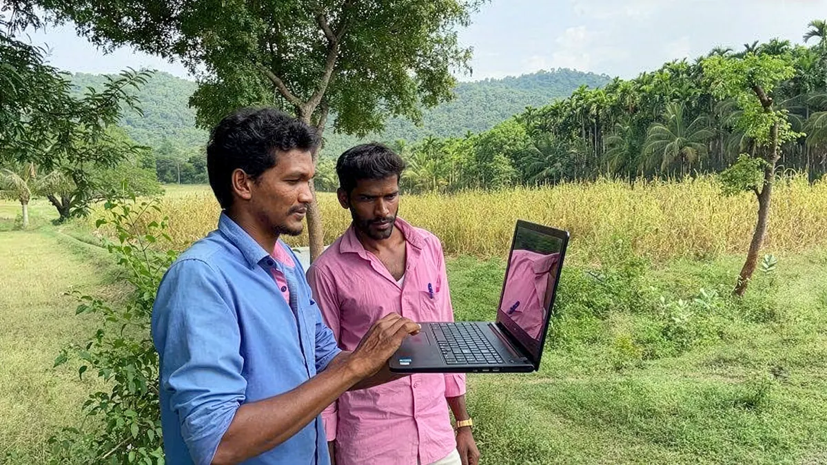 A young woman showing a laptop to an elderly village woman